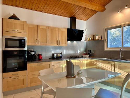 une cuisine avec des armoires en bois et une table avec des chaises dans l'établissement Villa Zénith - Piscine chauffée & Paillotte Bambou, à Nîmes