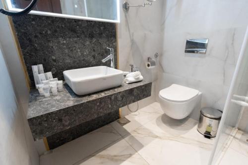 a white bathroom with a sink and a toilet at فندق الماسة للأجنحة الفندقية in Tripoli