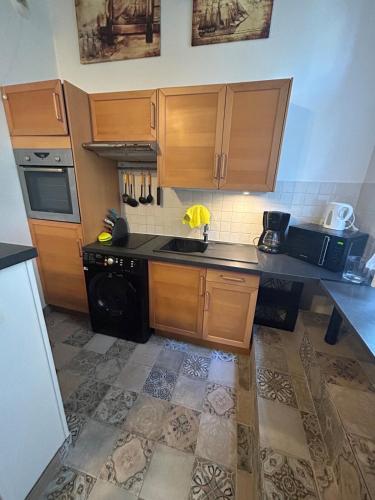 - une cuisine avec des placards en bois et un lave-vaisselle noir dans l'établissement L'escapade en mezzanine, à Dieppe