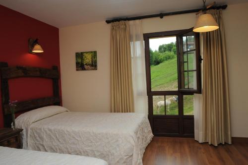 a bedroom with two beds and a large window at El Quesar de Gamoneo in Gamonedo de Cangas
