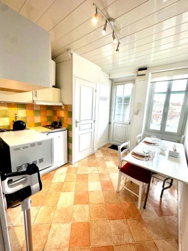 La cuisine est équipée d'une table et de plaques de cuisson blanches. dans l'établissement Appartement en plein centre-ville Gare Darcy, à Dijon