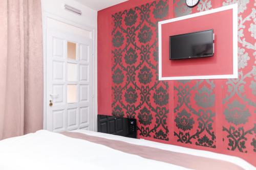 a bedroom with a red wall with a tv on it at SPA apartman Tomin adults only in Soko Banja
