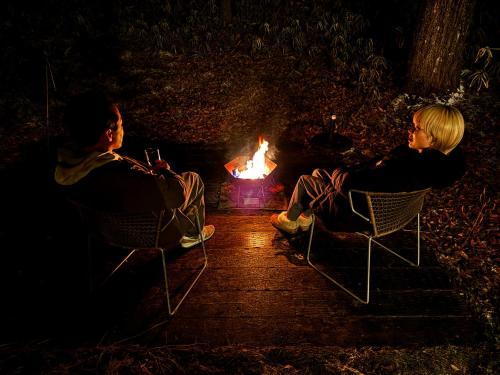 two people sitting in chairs in front of a fire at BBQ&焚火OK - the Hours KARUIZAWA in Karuizawa