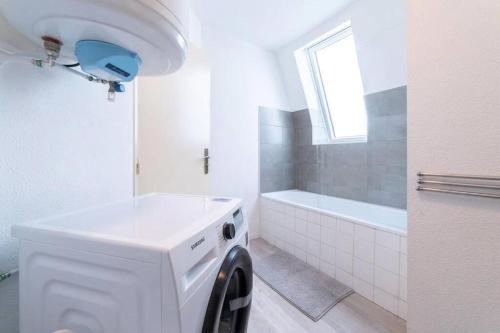 - un lave-linge blanc dans la salle de bains pourvue d'une fenêtre dans l'établissement Franklin City, à Mulhouse