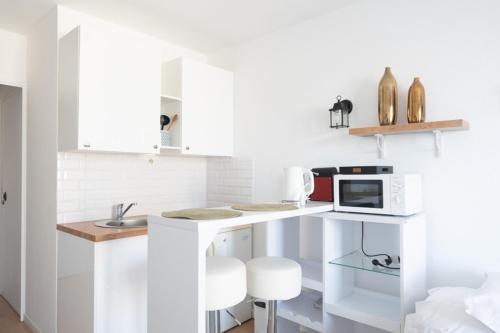 une cuisine blanche avec un évier et un micro-ondes dans l'établissement Charming studio in Saint-Denis, à Saint-Denis