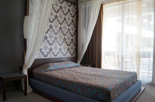 a bedroom with a bed and a window with curtains at Regina Maria Spa Design Hotel in Balchik