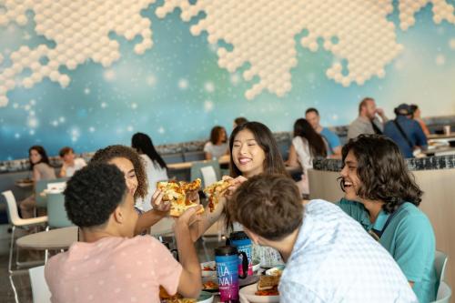 a group of people sitting at a table eating pizza at Universal's Stella Nova Resort in Orlando