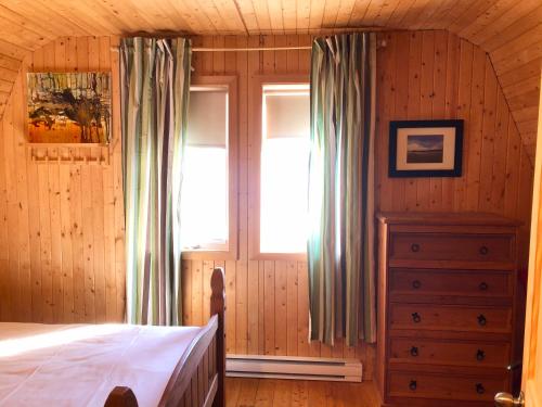 a bedroom with a bed and a window and a dresser at Chalets du bout du monde in Gaspé