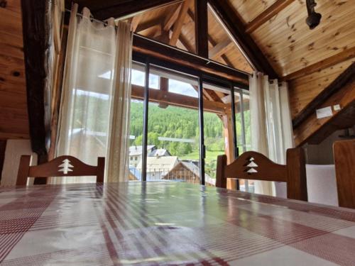 une table à manger avec deux chaises et une grande fenêtre dans l'établissement Chalet 11 pers, 5 ch, pied des pistes, balcon, parking, Wi-Fi, cheminée, Serre Chevalier - FR-1-762-27, à Saint-Chaffrey