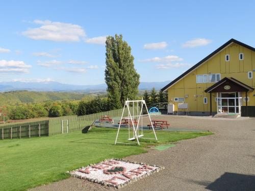 une aire de jeux devant un bâtiment jaune dans l'établissement B&B Ken&Mary, à Biei