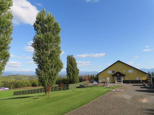 a barn with a yard and a tree at B&B Ken&Mary in Biei