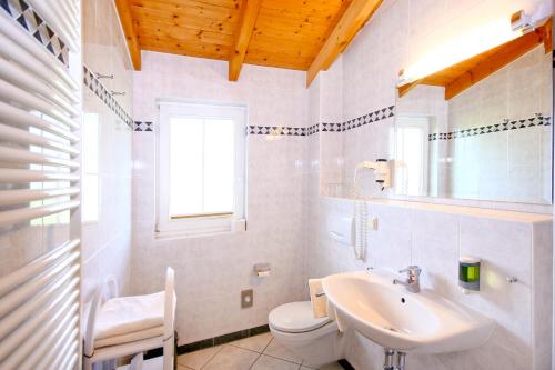 a white bathroom with a sink and a toilet at Hotel Garni Getreuer Eckart in Binz