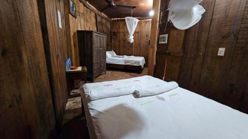 a bedroom with two beds in a room with wooden walls at Cabaña Velo de Novia in Socoltenango