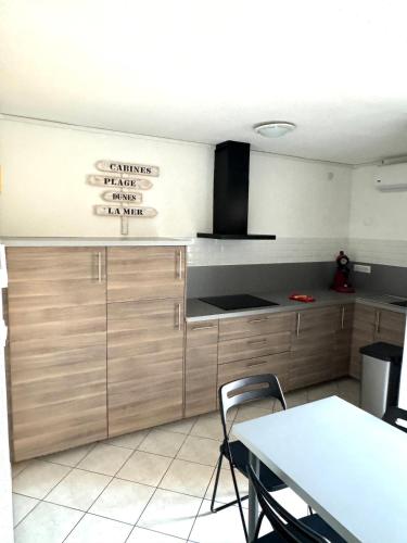- une cuisine avec des placards en bois, une table et une pancarte dans l'établissement coquet appartement 1 chambre avec parking bord de plage, à Sète