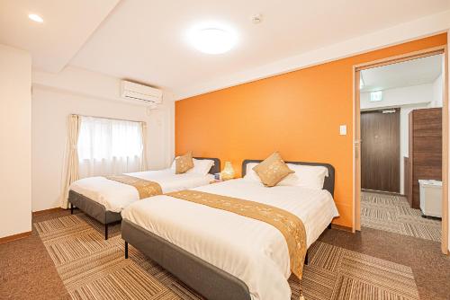 two beds in a hotel room with orange walls at 鵜の木民宿101号室鵜の木駅から徒歩4分とても便利の場所 in Tokyo