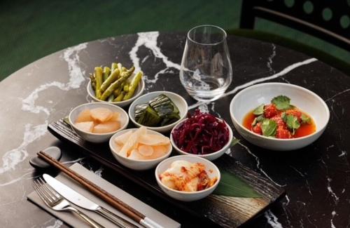 a table with bowls of food and a glass of wine at Skostredet Hotel in Bergen