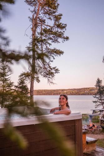a woman sitting in a bath tub next to a lake at Chalets du bout du monde in Gaspé