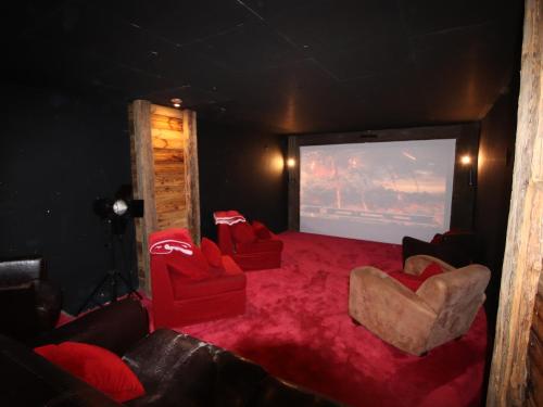 une chambre avec deux chaises rouges et un écran de projection dans l'établissement Prestigious Chalet with Pool & Hot tub, Mountain Views for 19 Guests, à Vars