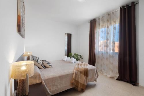 a white bedroom with a bed and a window at Apartamento Rincon Tropical in Candelaria