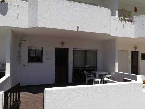 a white house with a balcony with a table and chairs at Baleal Time Out in Ferrel