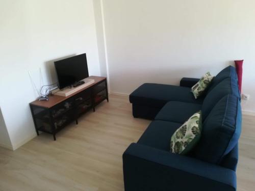 a living room with a blue couch and a tv at Baleal Time Out in Ferrel