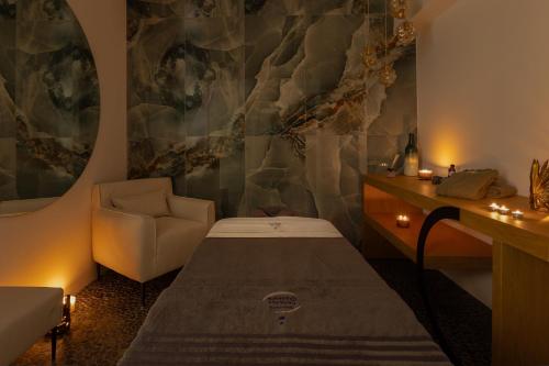 a room with a bed and a chair in it at Santo Mangata Boutique Hotel and Spa in Perissa