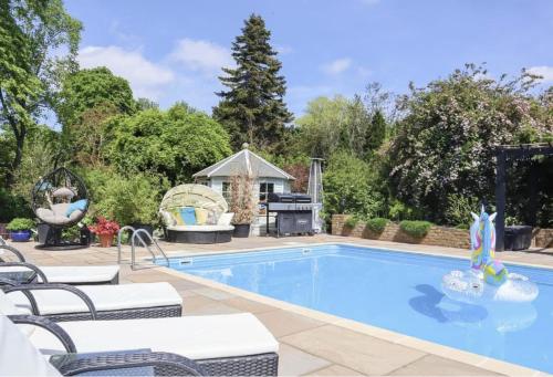 a swimming pool with chairs and a grill in a yard at The Manor Coach House in Canterbury