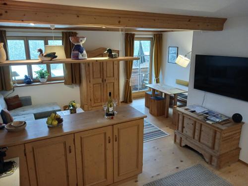a living room with a flat screen tv and a kitchen at Landhaus am Bergfeld in Bayrischzell