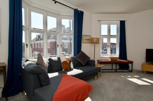 a living room with a couch and windows at Beautiful large 3-bed coastal flat with parking. in Frinton-on-Sea
