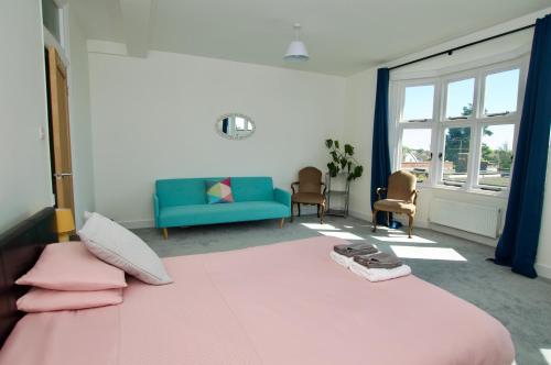 a bedroom with a pink bed and a blue couch at Beautiful large 3-bed coastal flat with parking. in Frinton-on-Sea