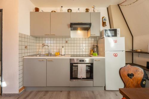  La cuisine est équipée de placards blancs et d'un réfrigérateur. dans l'établissement Logement Traditionnel au Style Alsacien Central, à Mulhouse
