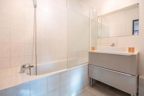 une salle de bain blanche avec une baignoire et un lavabo dans l'établissement Logement Traditionnel au Style Alsacien Central, à Mulhouse