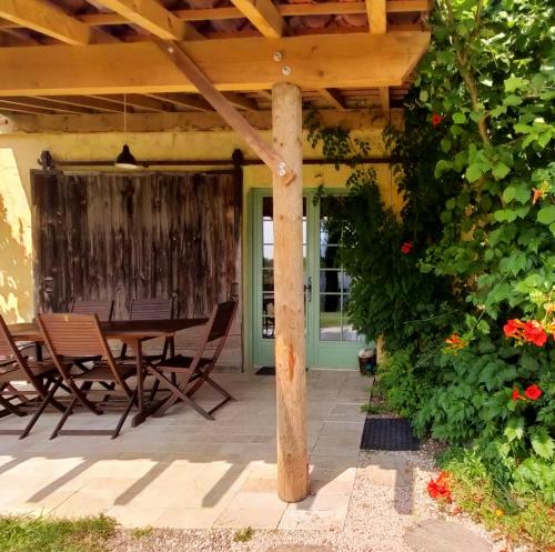a patio with a table and chairs under a wooden pergola at les Didascalies in Vic-Fezensac