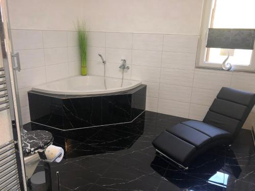 a bathroom with a bath tub and a chair at Müritz Apartments in Waren