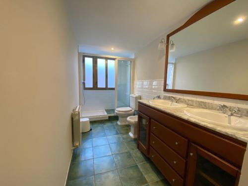 a bathroom with two sinks and a toilet and a mirror at Housingcoruña Apartamento Playa Miño 01 in Miño