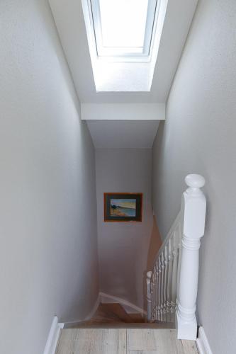 ein Treppenhaus mit Oberlicht und weißem Treppenaufgang in der Unterkunft Strand Brise in Westerland
