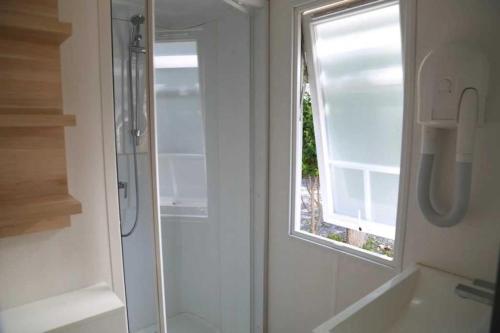 La salle de bains est pourvue d'une douche et d'une fenêtre. dans l'établissement Camping 4 étoiles - Piscine - ccaffbg, à Villeneuve-lès-Béziers