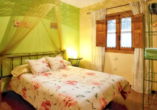 ロブレディージョ・デ・ガタにあるCharming House in Robledillo de Gata with Fireplace and Terraceのベッドルーム1室(花柄の掛け布団付きのベッド1台付)