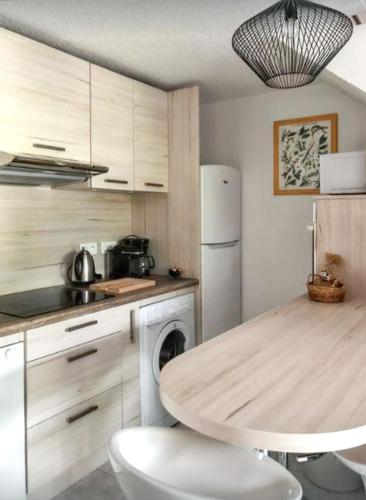 une cuisine avec une table et un réfrigérateur blanc dans l'établissement Maison conviviale à Lecci avec piscine partagée 70 m² 8 personnes, à Lecci