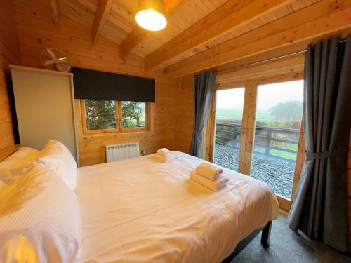 a bedroom with a bed with two towels on it at Pass the Keys Beautiful Countryside Lodge with Outstanding Views in Dumfries