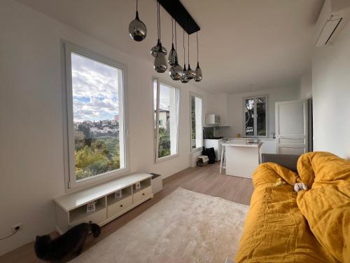 un salon avec un canapé et une cuisine avec des fenêtres dans l'établissement Petit paradis perché au coeur de Nice, à Nice