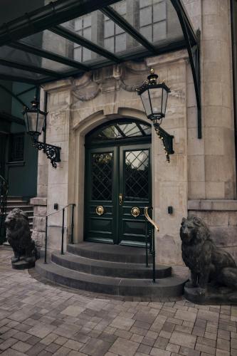 a green door on a building with two statues at Hotel Villa Achenbach in Düsseldorf