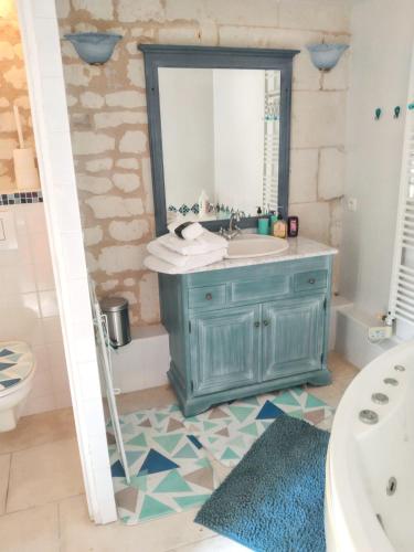 La salle de bains est pourvue d'une coiffeuse bleue et d'un miroir. dans l'établissement Maison charmante à Courchamps avec vue sur jardin, à Courchamps
