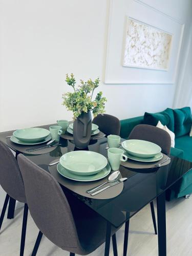 a black table with chairs and plates and a vase with flowers at Adam Residence in Oradea