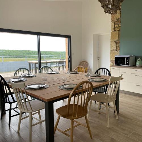 a dining room table with chairs and a large window at Hitton Séjours Nature in Biran