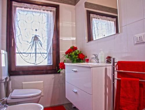 un bagno con un water, un lavandino e una finestra di The History Apartment a Montagnana