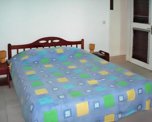 a bed with a blue and yellow comforter in a bedroom at Maison spacieuse avec piscine privée à Le François in Le François
