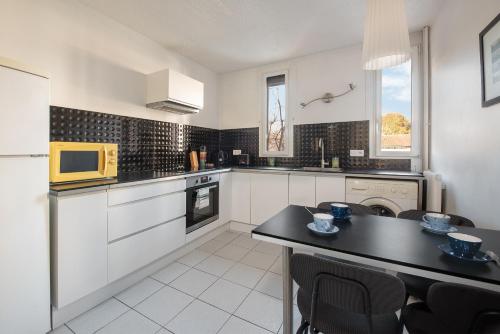 une cuisine avec des placards blancs et une table noire dans l'établissement T3 Centre ville à 2 pas du métro - parking gratuit, à Toulouse