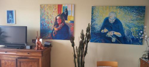 - un salon avec des peintures murales et une télévision dans l'établissement Chez Janie, à Nantes