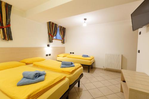 two beds in a room with yellow sheets at Appartamenti Elena & Milva in Livigno